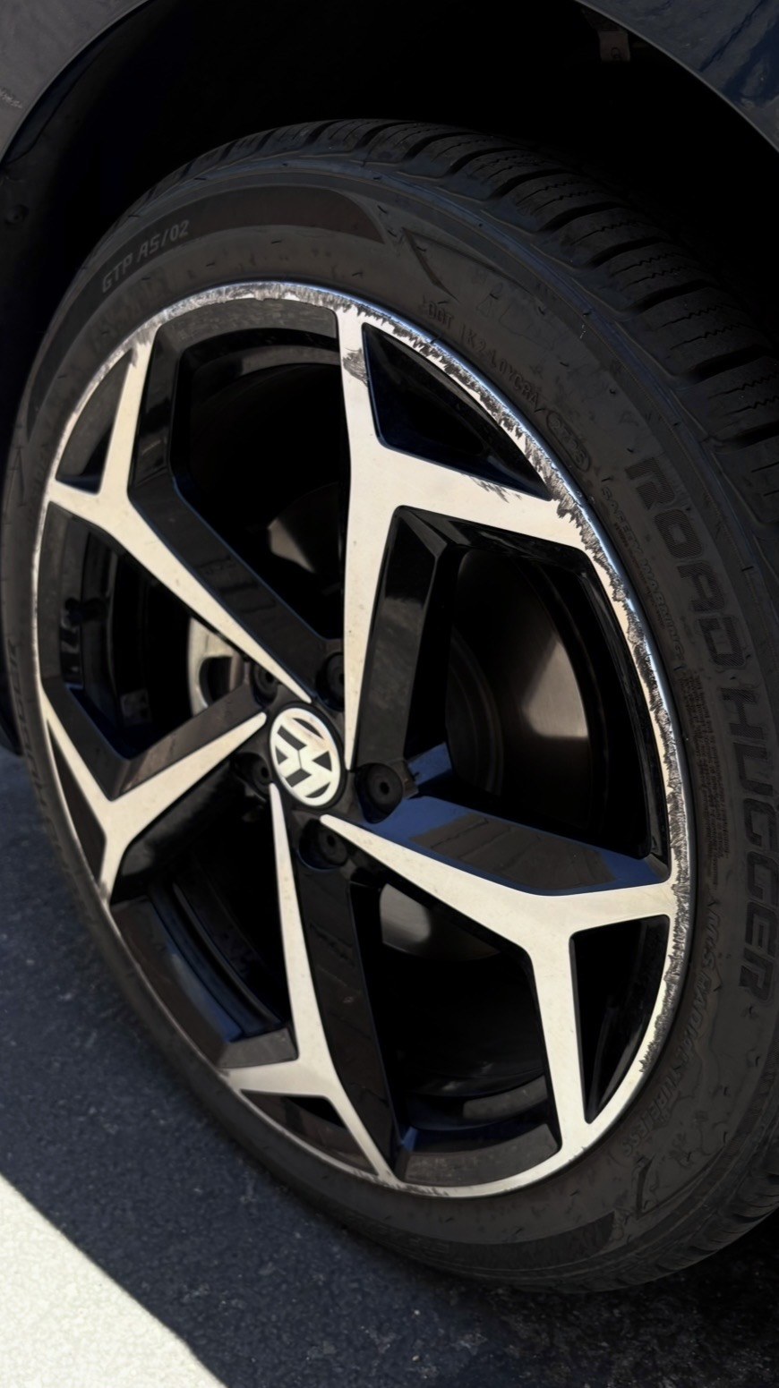 VW wheel before repair — curb rash along the machined lip